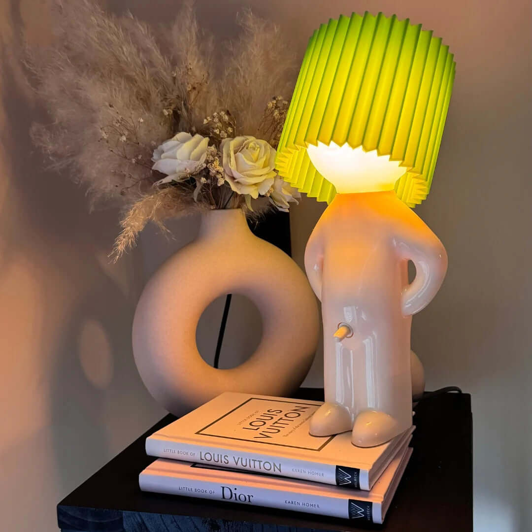 Bordslampa med fot i form av en stående figur – veckad lampskärm
